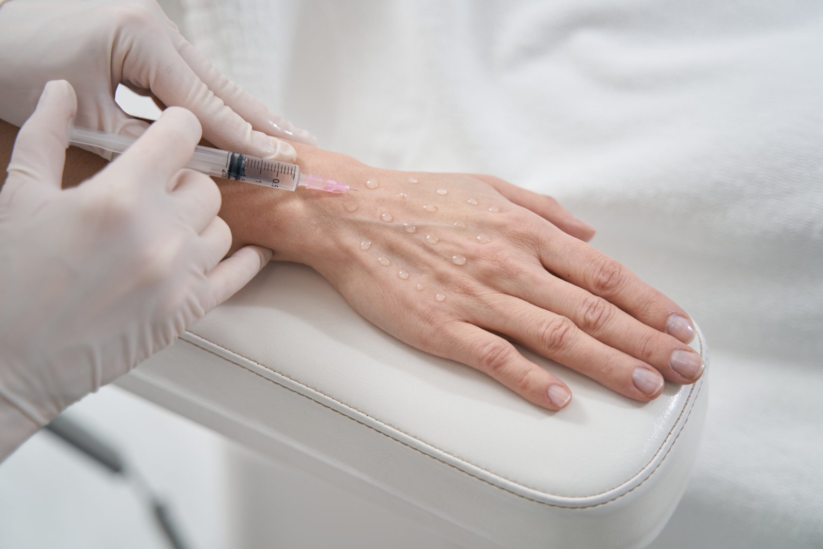 Woman receiving hand rejuvenation filler injection at Couture Dermatology and Laser